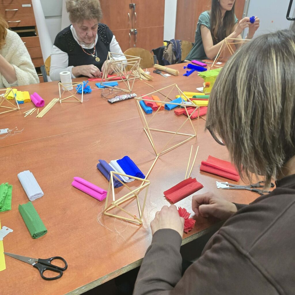 Uczestniczki warsztatów wspólnie tworzą pająki ludowe, zgłębiając tajniki słowiańskiego rzemiosła i zdobnictwa wnętrz.