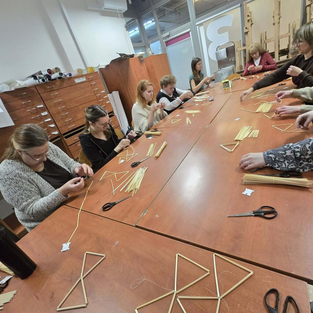 Uczestniczki warsztatów wspólnie tworzą pająki ludowe, zgłębiając tajniki słowiańskiego rzemiosła