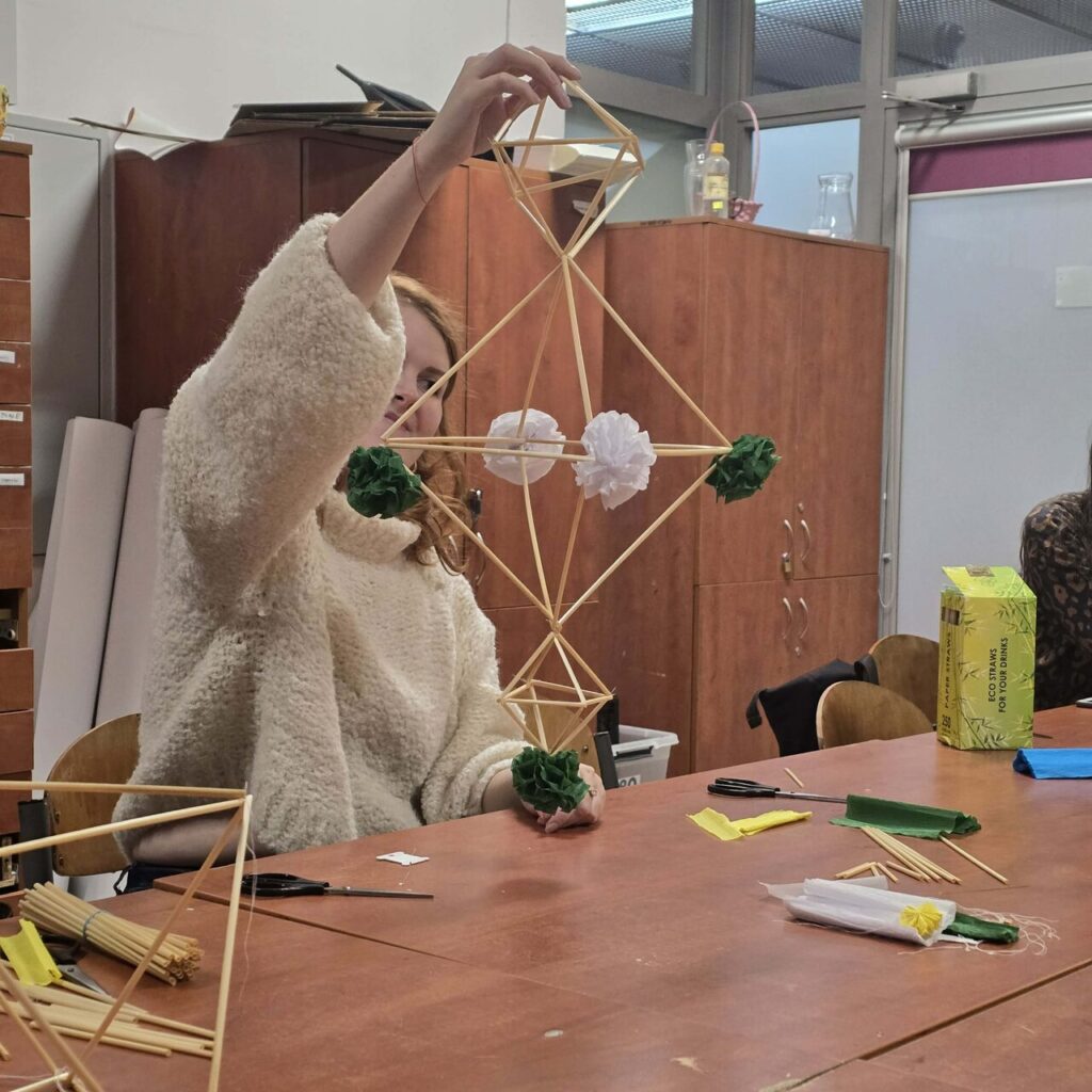 Uśmiechnięte uczestniczki prezentują własnoręcznie wykonane pająki ludowe – pamiątki z warsztatów kultury słowiańskiej.